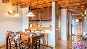 Una mesa de comedor de madera con sillas, una zona de cocina con armarios de madera y un arreglo floral decorativo.