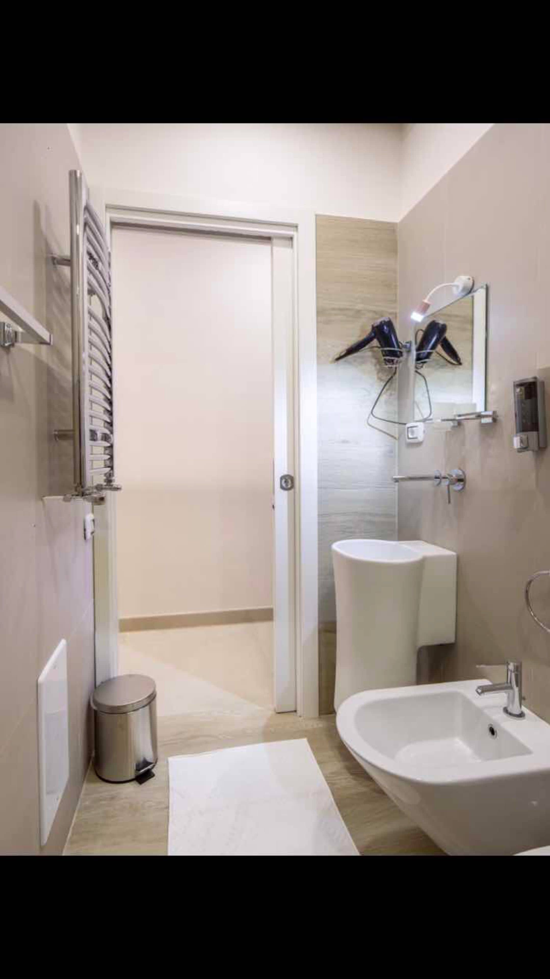 A modern bathroom with a white sink, a mirror, and a shower area.