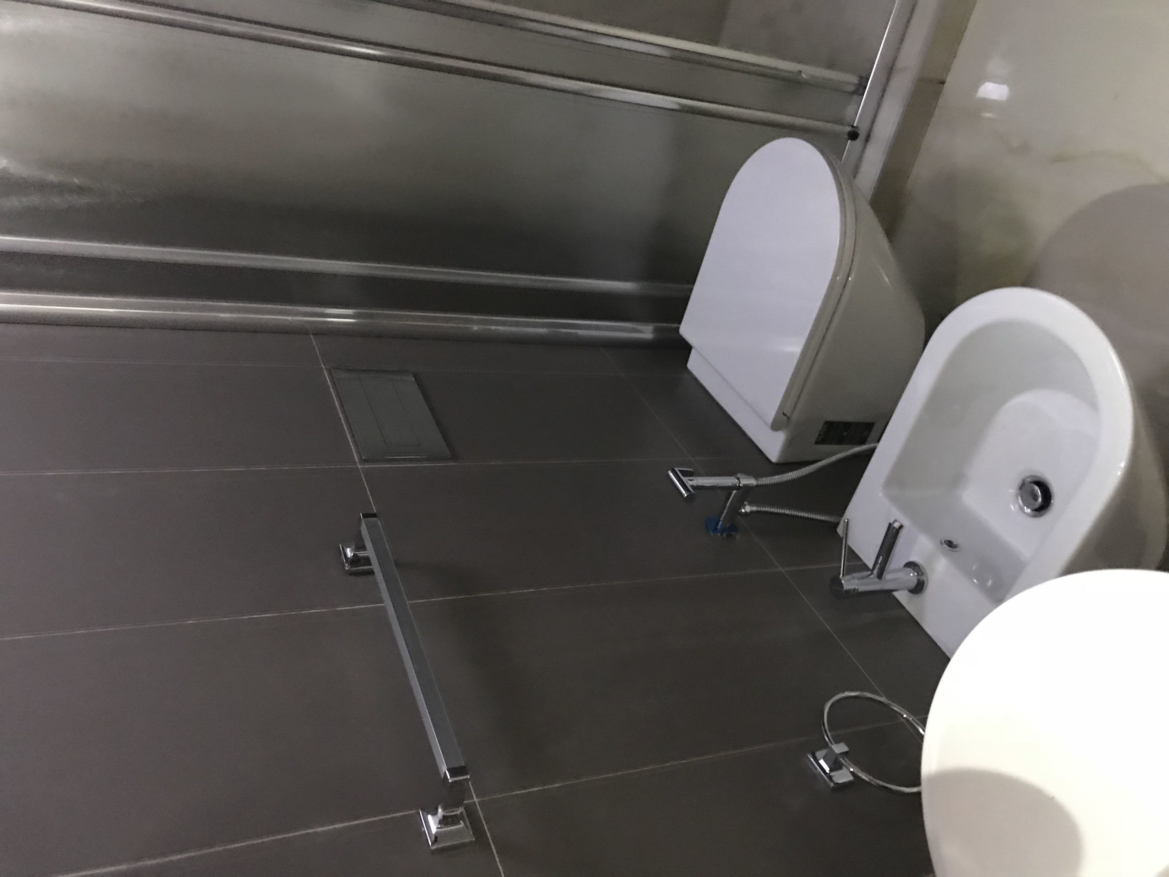 A modern bathroom with a white toilet, a bidet, and a shower area.
