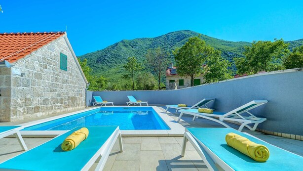 Un espace piscine avec des chaises longues et un bâtiment en pierre.