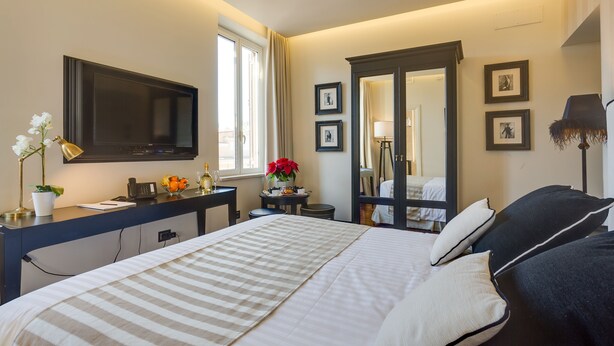 A hotel room with a large bed, a desk with a computer, a TV, and a mirror. - Luxury B&B room at Colosseum bathroom ensuite (Roma)