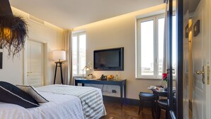 A hotel room with a bed, a desk with a TV, a window, and a door. - Luxury B&B room at Colosseum bathroom ensuite (Roma)