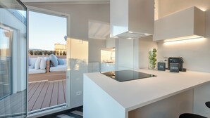 Eine moderne Küche mit einer Kochinsel aus Glas, einem eingebauten Backofen und einer Kaffeemaschine.