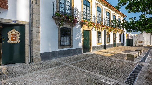 Un bâtiment historique doté d’une cour pavée, de grandes fenêtres et d’une porte verte.