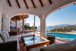 A terrace with a pool, outdoor seating, and a view of the sea.