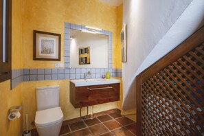 Bathroom features a toilet, vanity with mirror, and a small window with a view.