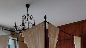 A four-poster bed with a floral bedspread, a wooden floor, and a wooden wall.