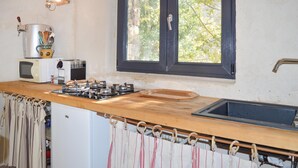 Una cocina con encimera de madera, estufa a gas, lavamanos, ventana y microondas.