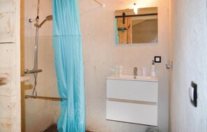Un baño con ducha, lavabo y espejo.
