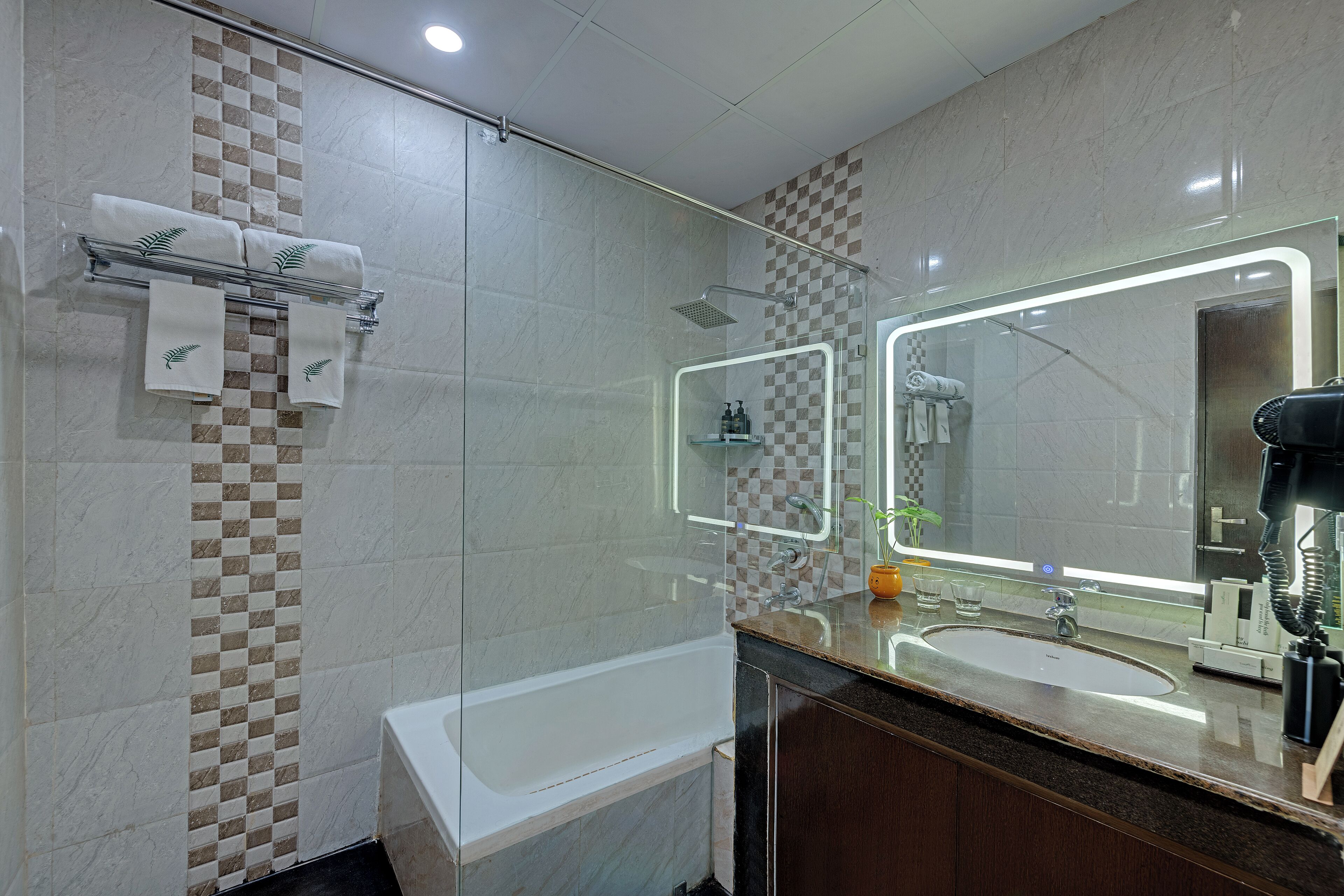 Un baño moderno con ducha envuelta en vidrio, un espejo grande y un lavamanos.