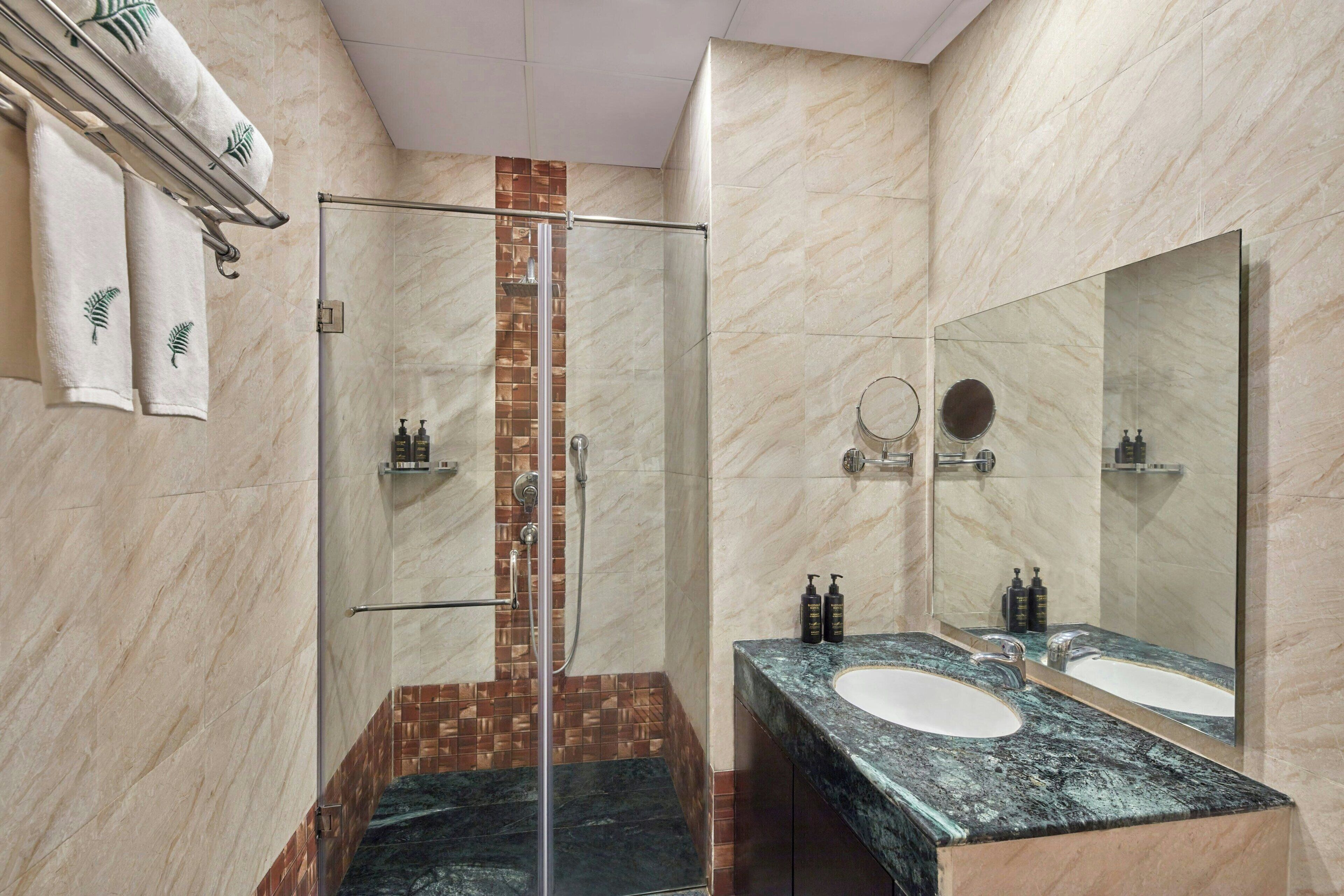A modern bathroom with a glass shower enclosure, a double sink vanity, and a large mirror.