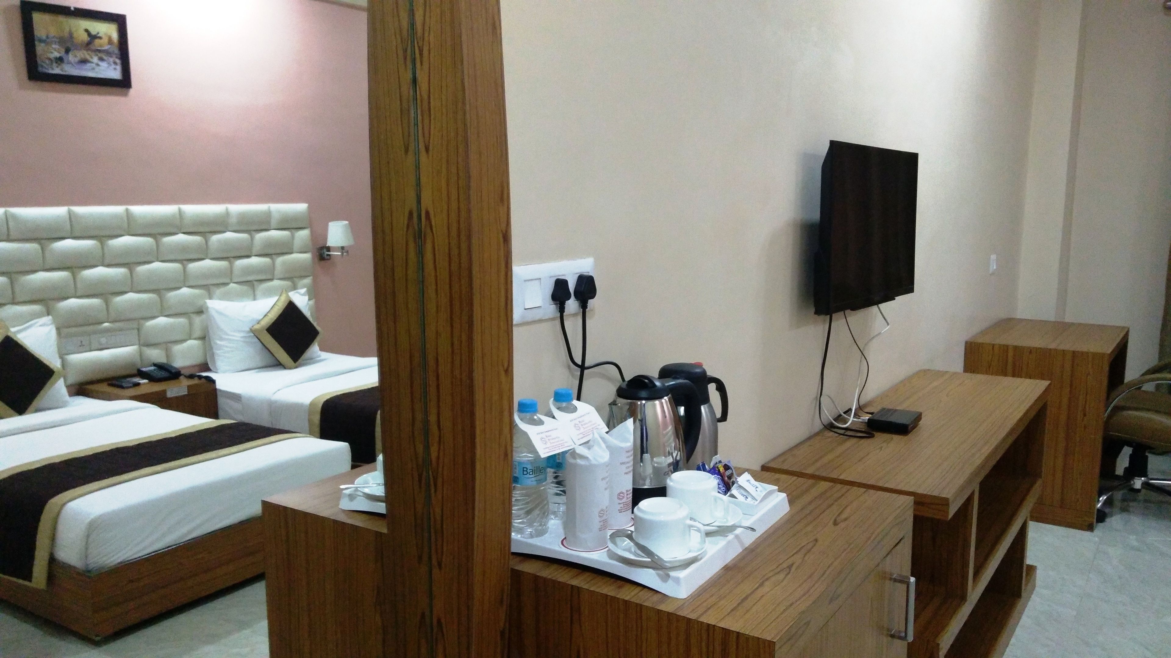 A hotel room with two beds, a wooden desk, a television, and a coffee maker.