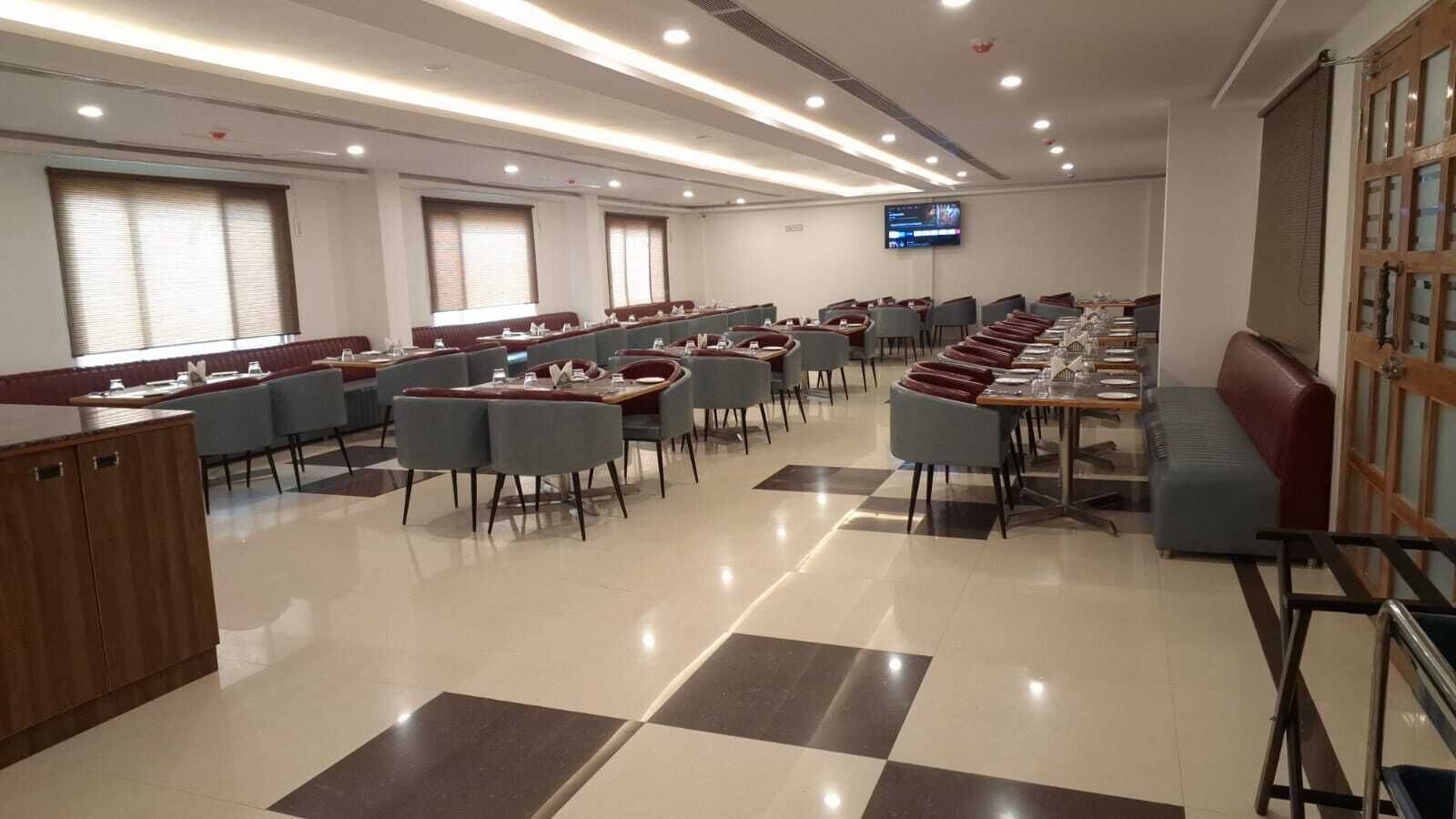 A modern conference room with long tables and chairs, a television screen, and a checkered floor pattern.