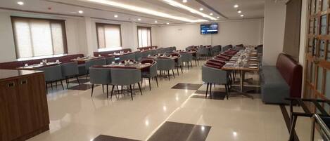 A modern conference room with long tables and chairs, a television screen, and a checkered floor pattern.