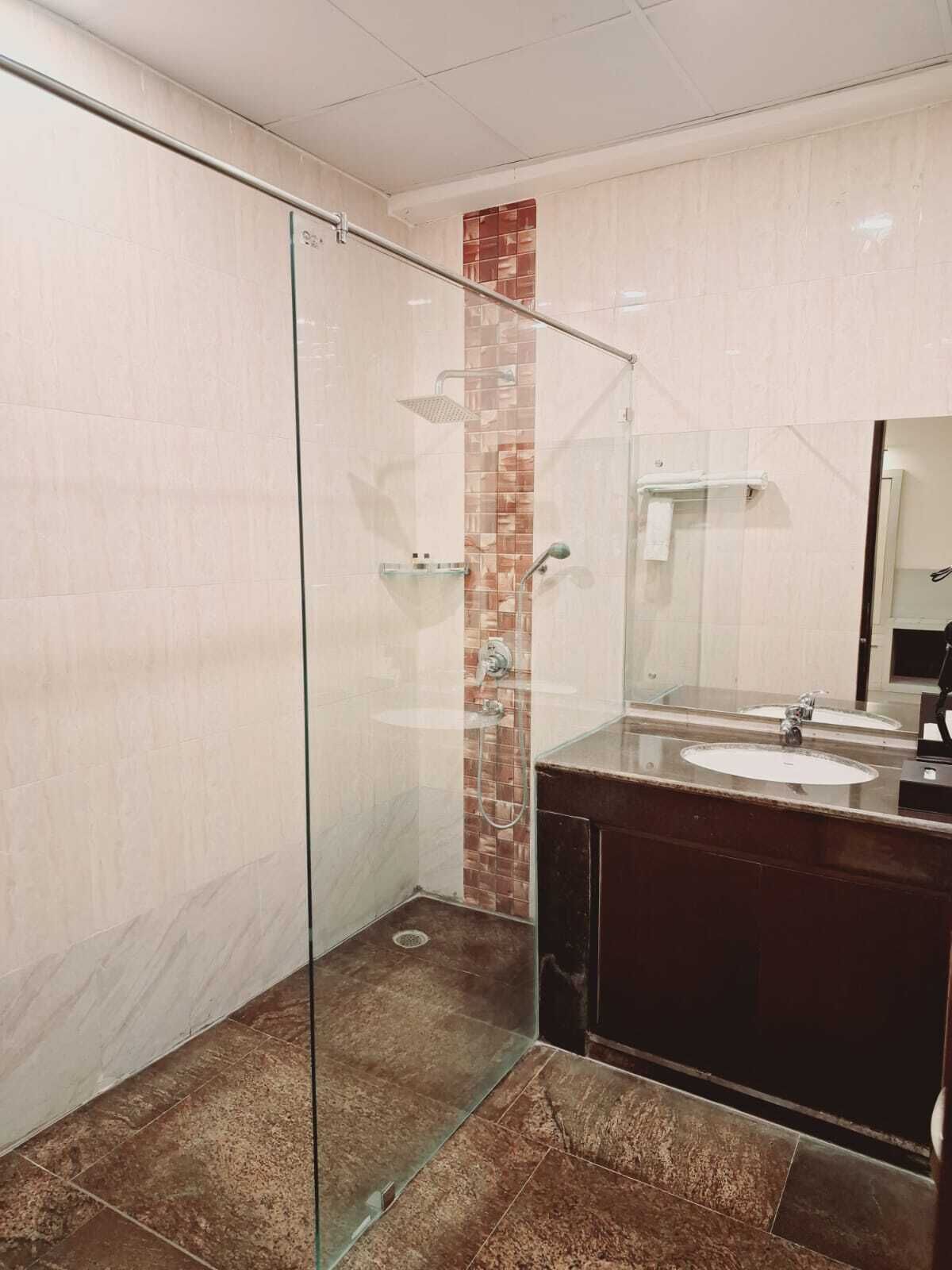 Ein modernes Badezimmer mit einer gläsernen Duschkabine, einem Waschtisch mit zwei Waschbecken und einer gefliesten Duschwand.