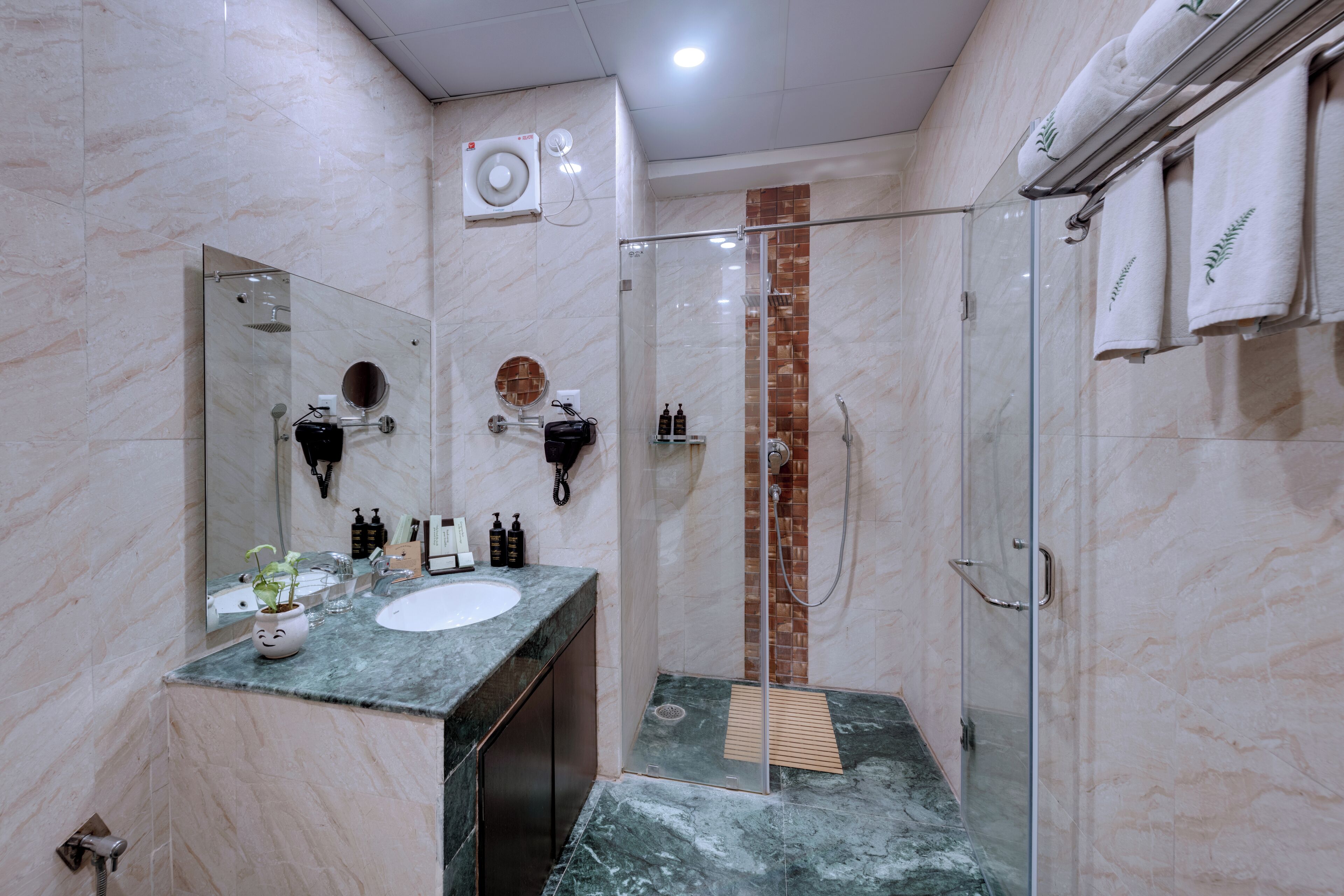 A modern bathroom with a marble sink, a glass-enclosed shower, and a towel rack.