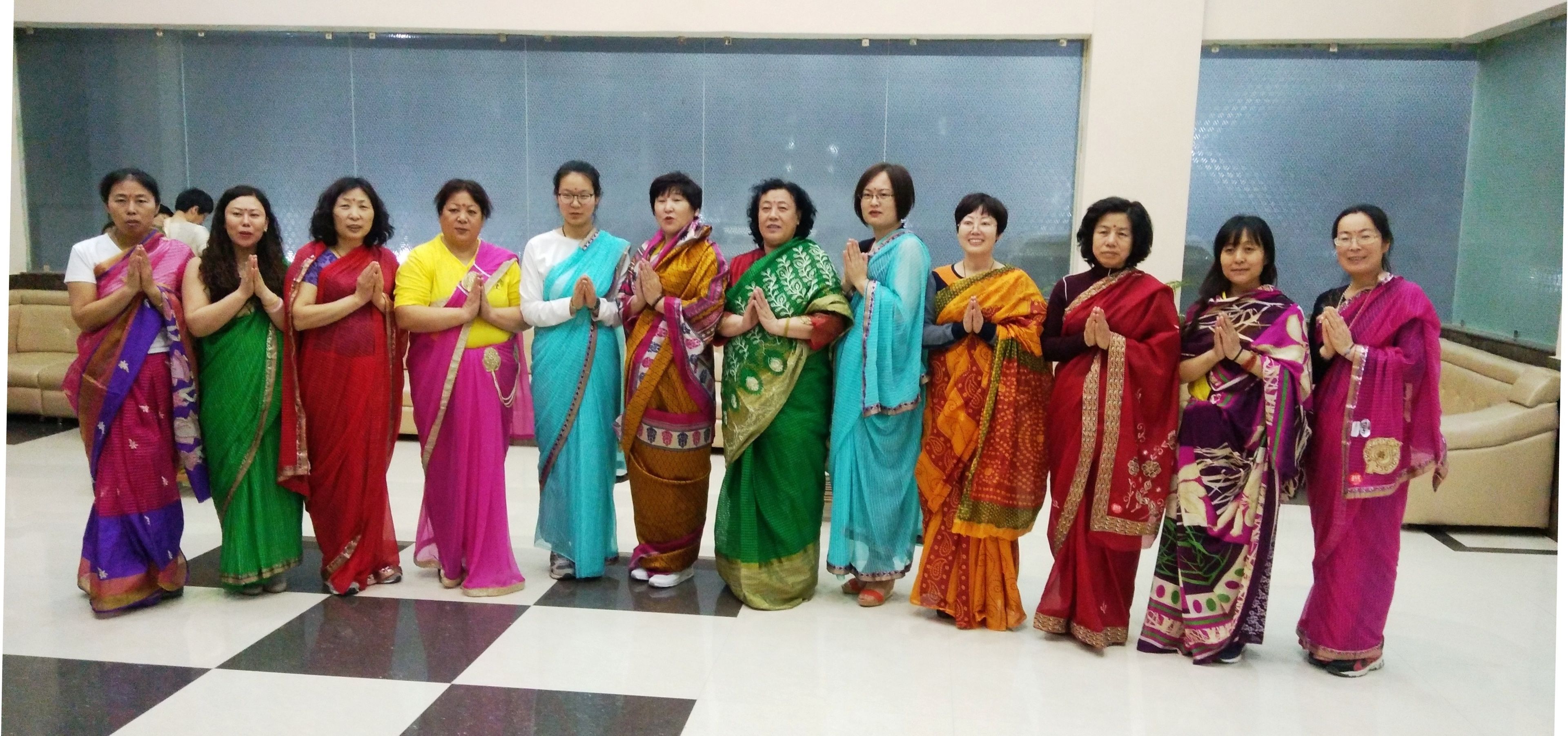 A group of people standing in a room with a checkered floor and a plain wall in the background.