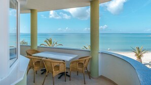 A balcony with a table and chairs, overlooking a beach and the ocean. - Beautiful apartment in Povljana (Povljana)