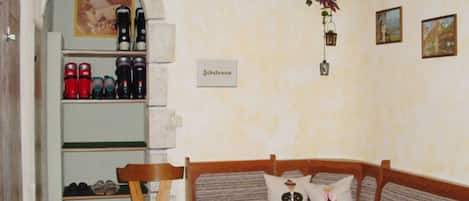 A cozy room with a wooden bench, a small table, and a shelf with various items.