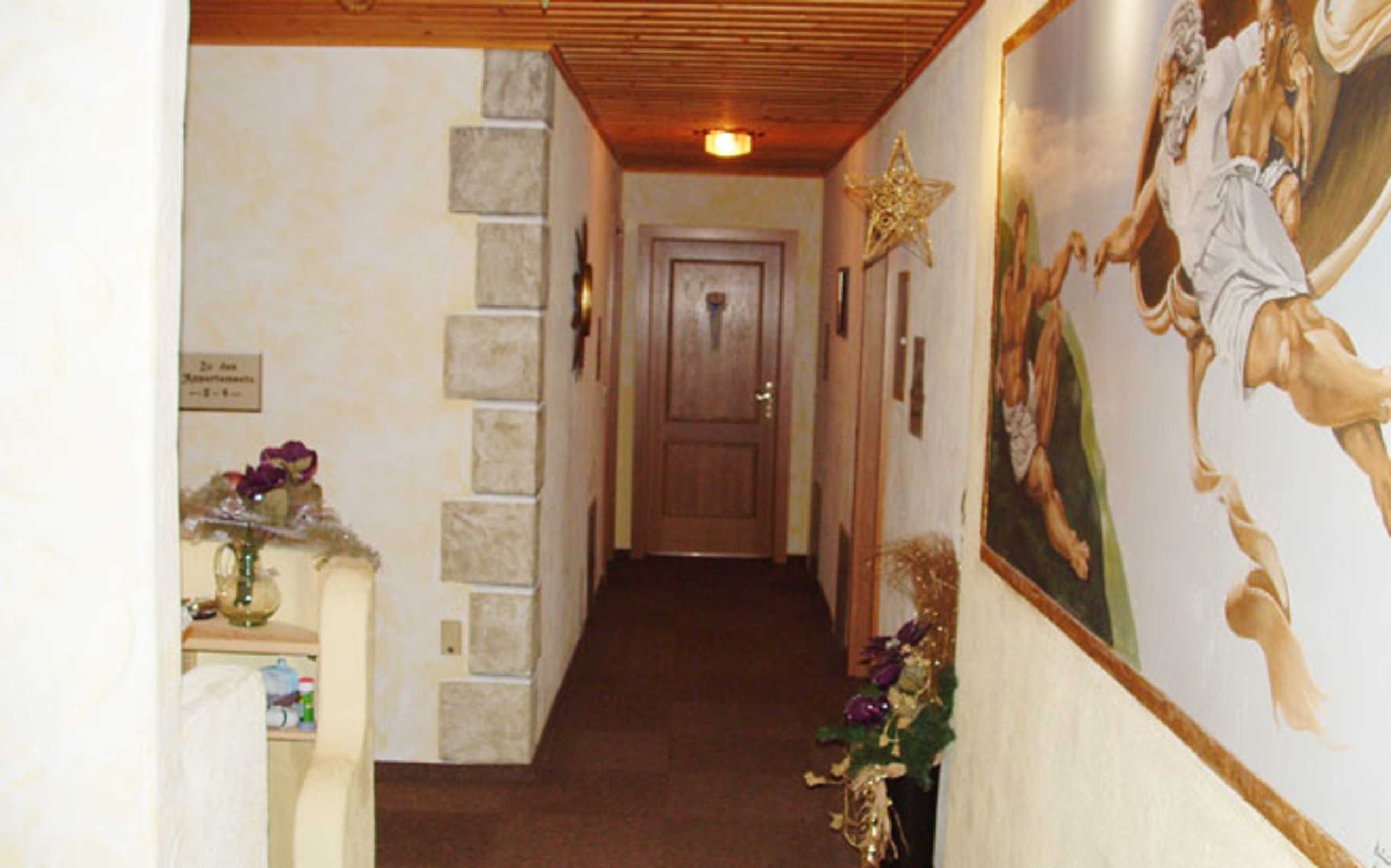 A hallway with a wooden ceiling, a stone wall, a wooden door, and a wall-mounted star decoration.