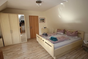 A bedroom with a bed, a wardrobe, a bedside table, and a door leading to a bathroom.