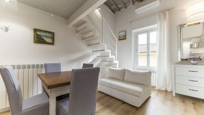 Un intérieur moderne comprenant un coin repas, un canapé, un escalier et une vue sur l’extérieur.