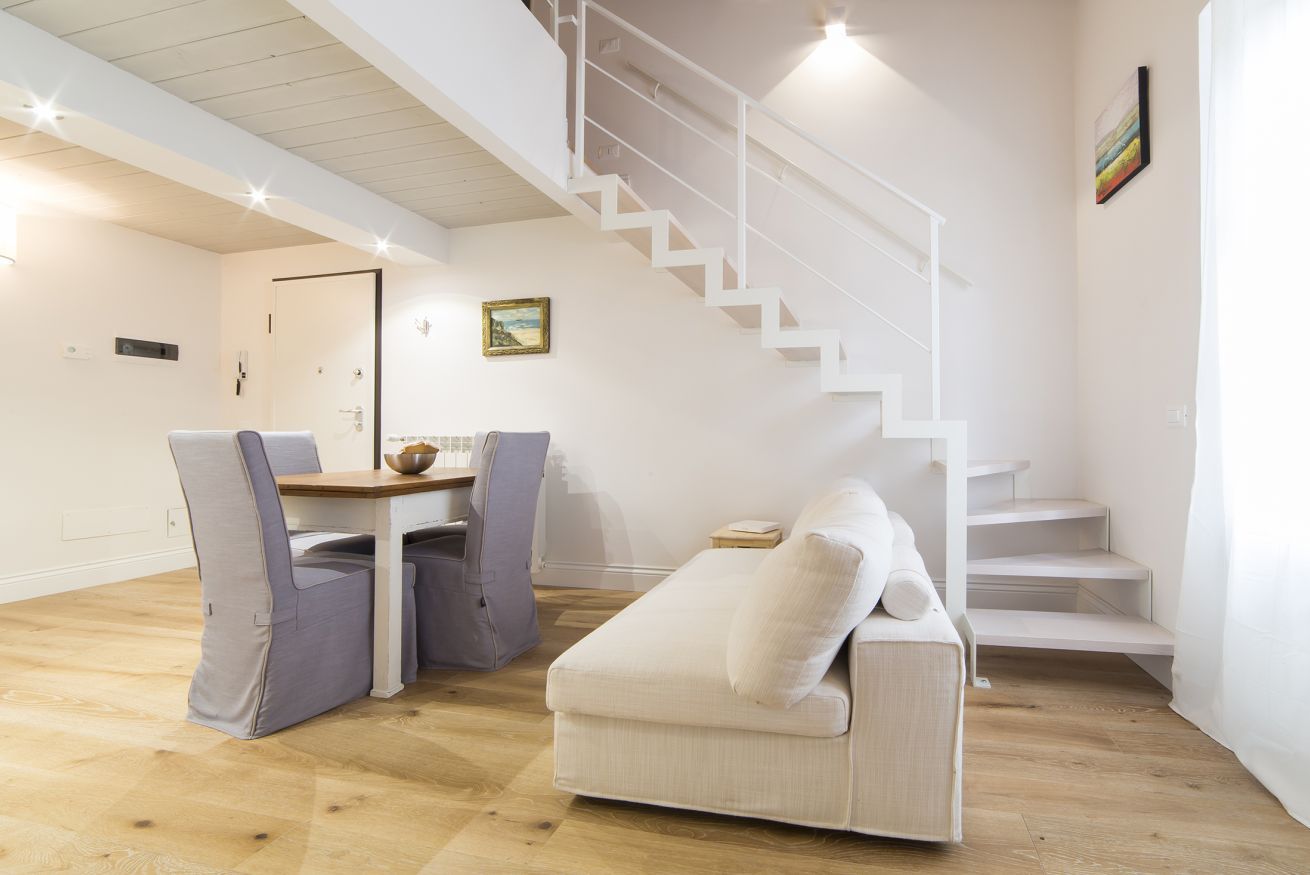 A modern interior with a staircase, a sofa, and a dining table.