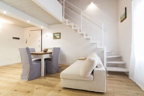 A modern interior with a staircase, a sofa, and a dining table.