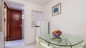 A small kitchen with a glass table, a white refrigerator, and a door leading to another room. - Beach front apartment in Starigrad with WiFi (Starigrad)