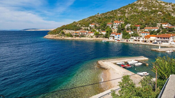 A coastal town with houses along the sea, a clear view of the water, and a hill in the background. - Beach front apartment in Starigrad with WiFi (Starigrad)