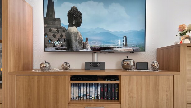 A television mounted on a wooden wall, displaying a Buddha statue with mountains in the background. - FeWo Galliet 1: 87sqm, 2 BR, balcony, quiet & close to trade fair (NRW)