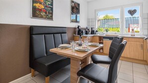 A modern kitchen with a dining area, including a wooden table, black chairs, and a black cushioned bench. - FeWo Galliet 1: 87sqm, 2 BR, balcony, quiet & close to trade fair (NRW)