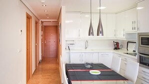 A modern kitchen with white cabinets, a stainless steel sink, and a dining area with a table and chairs.