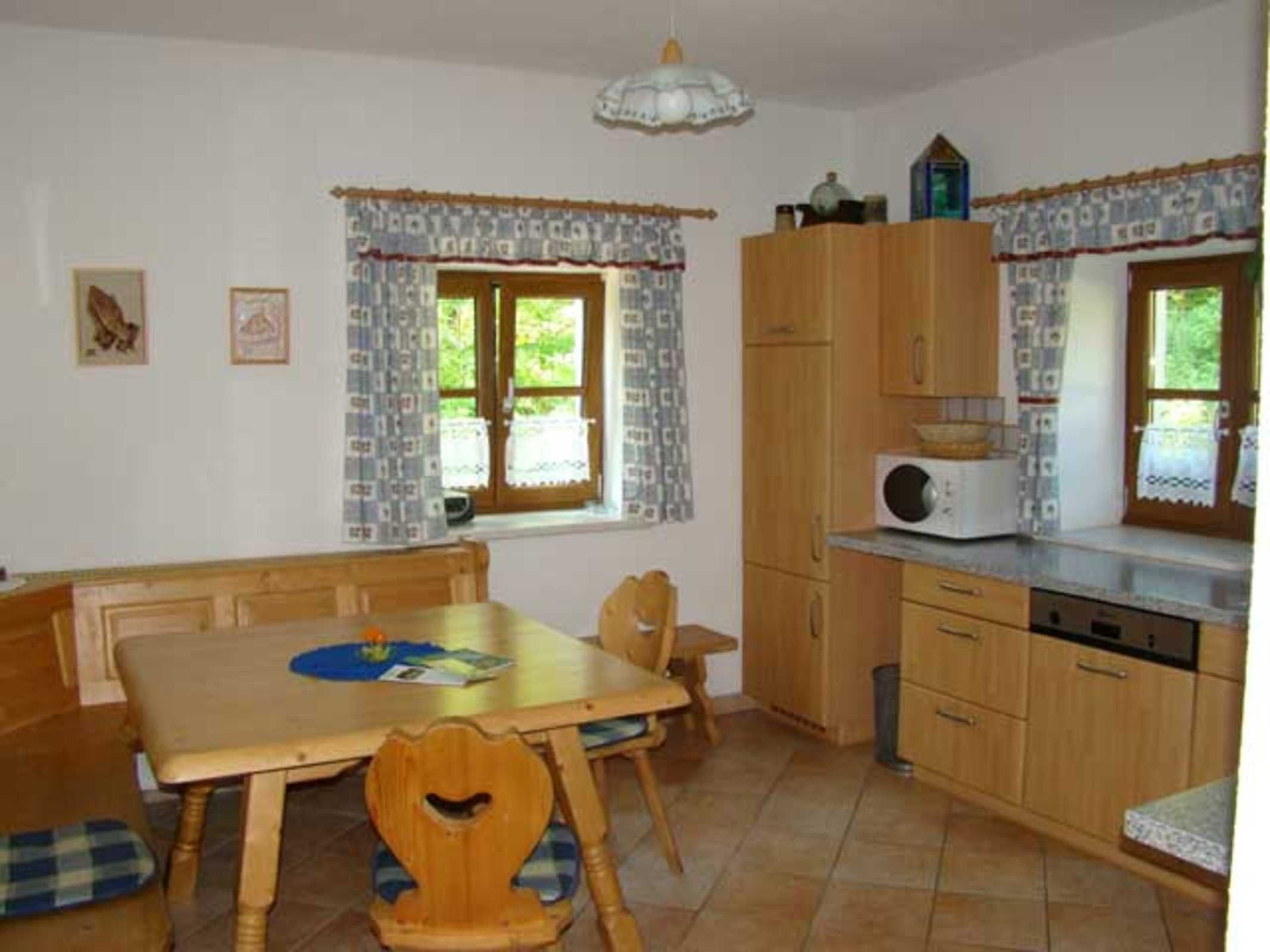 A kitchen with wooden cabinets, a microwave, and a dining table with chairs.