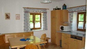 A kitchen with wooden cabinets, a microwave, and a dining table with chairs.