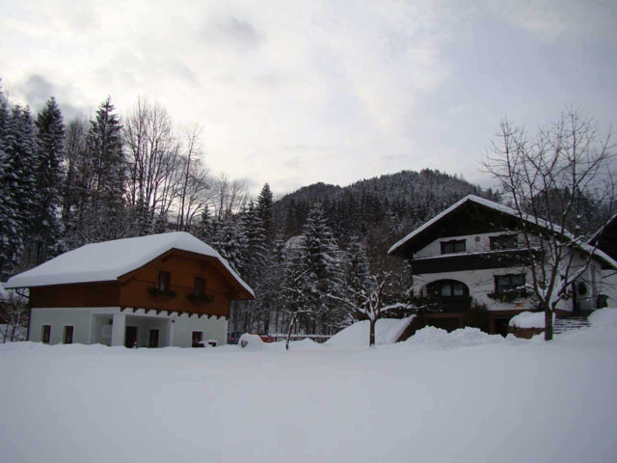 A snow-covered lodge with a wooden exterior, a large roof, and a mountainous backdrop.