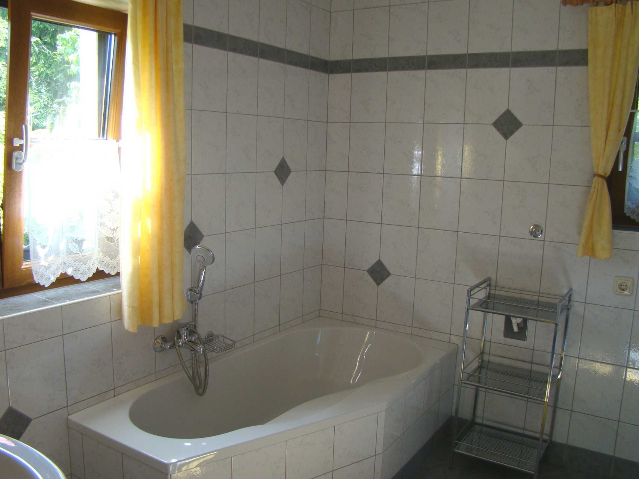 A bathroom with a bathtub, a shower, a sink, and a shelf.