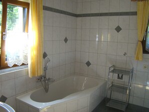 Une salle de bain avec une baignoire, une douche, un lavabo et une étagère.