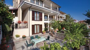 A multi-story building with balconies, outdoor seating, and potted plants. - Beautiful apartment in Rabac with WiFi (Rabac)