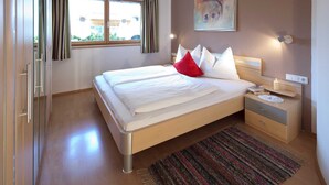 Una camera da letto con un letto, un comodino, una lampada e una finestra con tende.