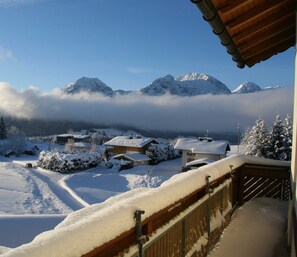 Un paysage de montagne enneigé, avec vue sur des maisons recouvertes de neige et un balcon en bois.