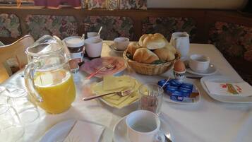 A breakfast table with various food items, a jug of juice, and a cup of coffee.