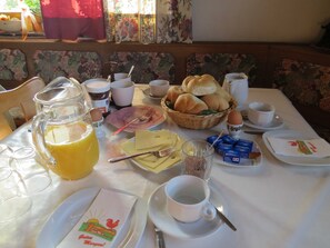 Una mesa de desayuno con diversos alimentos, una jarra de jugo y una taza de café.