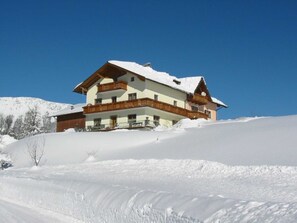 Un immeuble à plusieurs étages, doté de balcons, situé sur une pente enneigée.