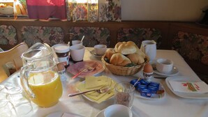 Une table de petit-déjeuner avec divers aliments, une carafe de jus et une tasse de café.
