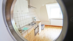 A kitchen with white cabinets, a stove, and a window. - Fewo Lerbachtal - Fewo Lerbachtal R3 2-4 persons (Osterode am Harz)
