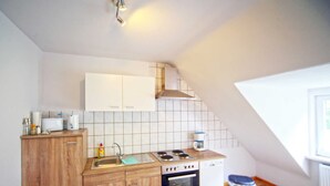 A kitchen with wooden cabinets, a sink, a stove, and a trash bin. - Fewo Lerbachtal - Fewo Lerbachtal R3 2-4 persons (Osterode am Harz)