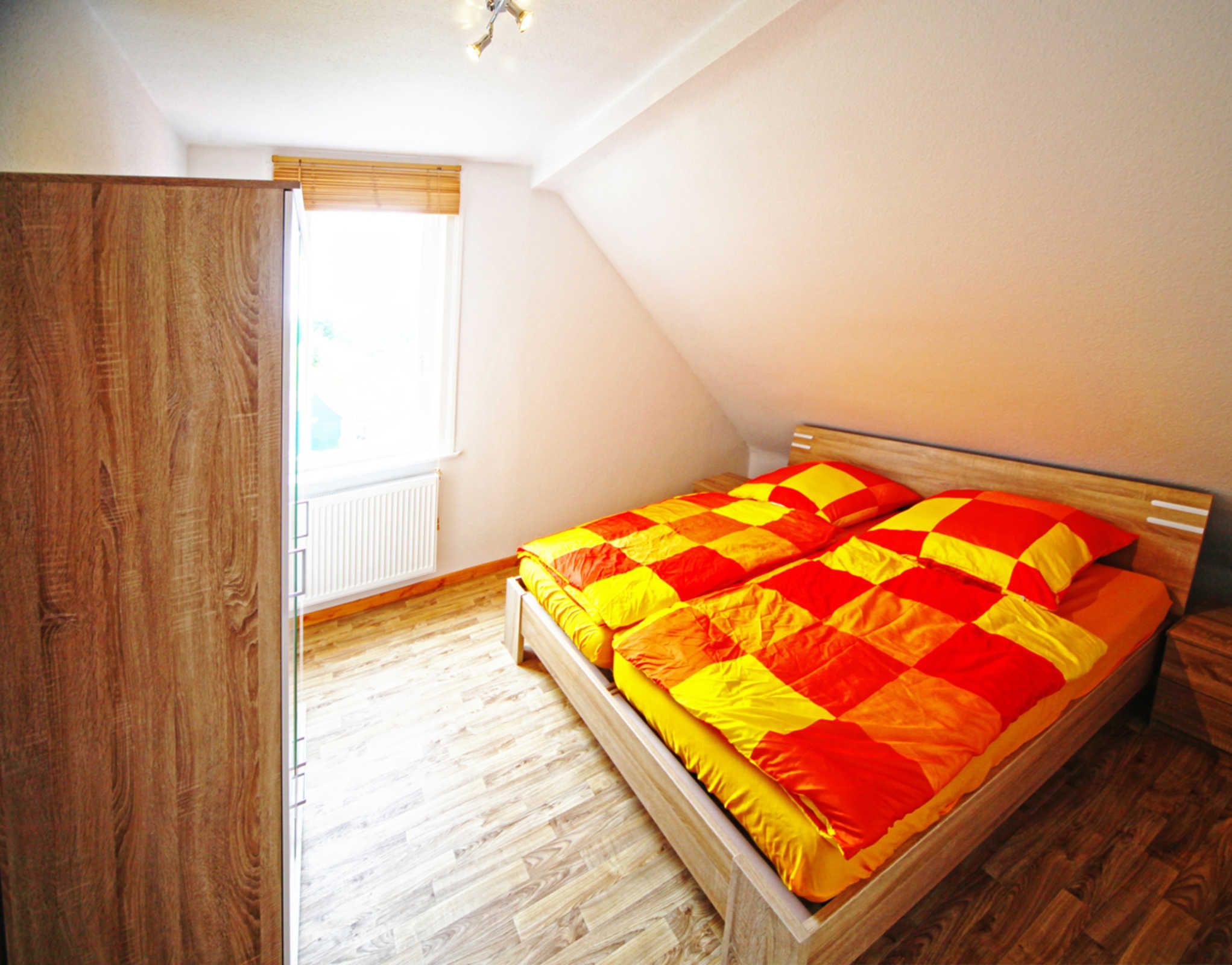A bedroom with a wooden bed, a window with blinds, and a radiator.