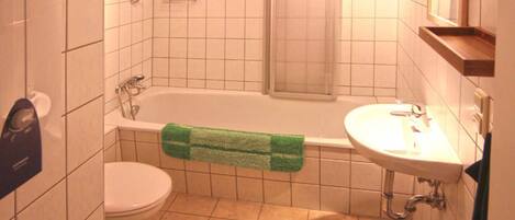 Une salle de bain comprenant des toilettes, une baignoire, un lavabo et un miroir.