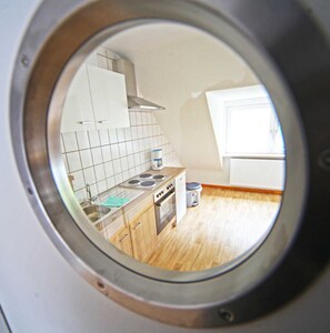 A kitchen with white cabinets, a stove, and a window.